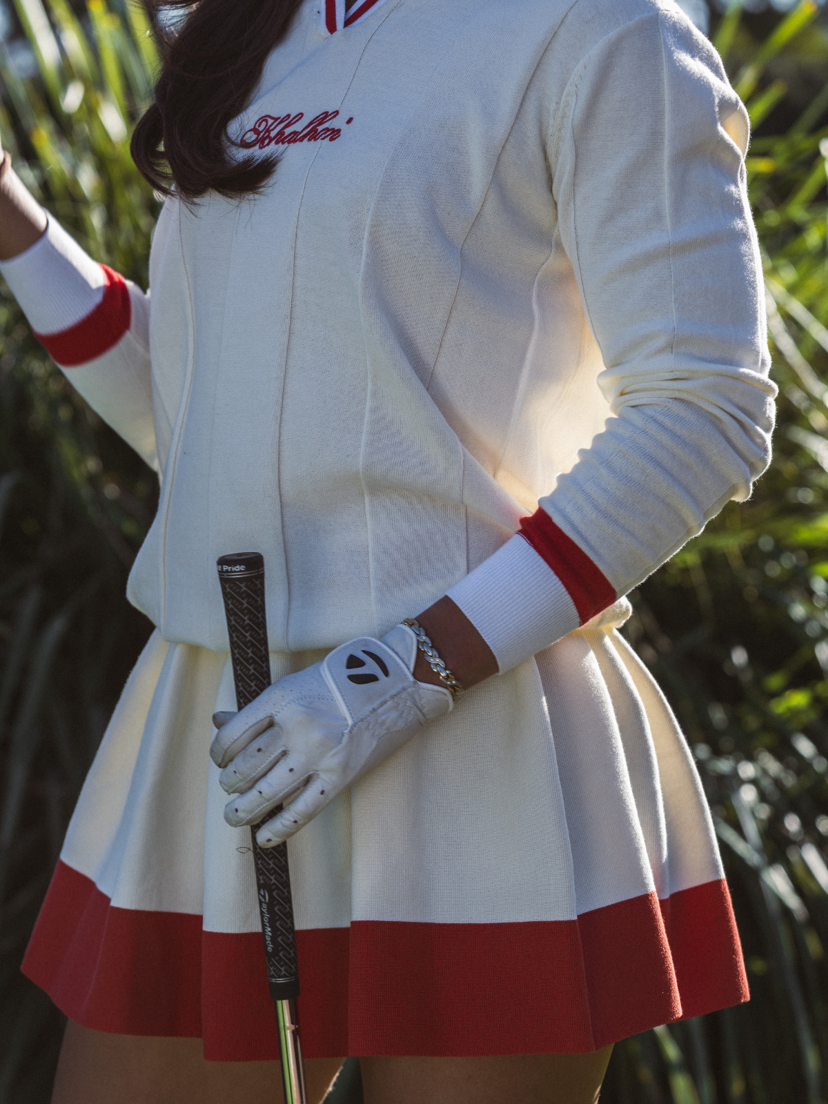 Close-up detail of Khalhon' cream and red knit skirt, showing embroidered logo and red hem trim