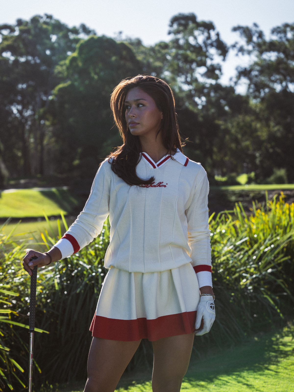 Woman wearing Khalhon' cream and red knit skirt and matching top on golf course, full length lifestyle shot