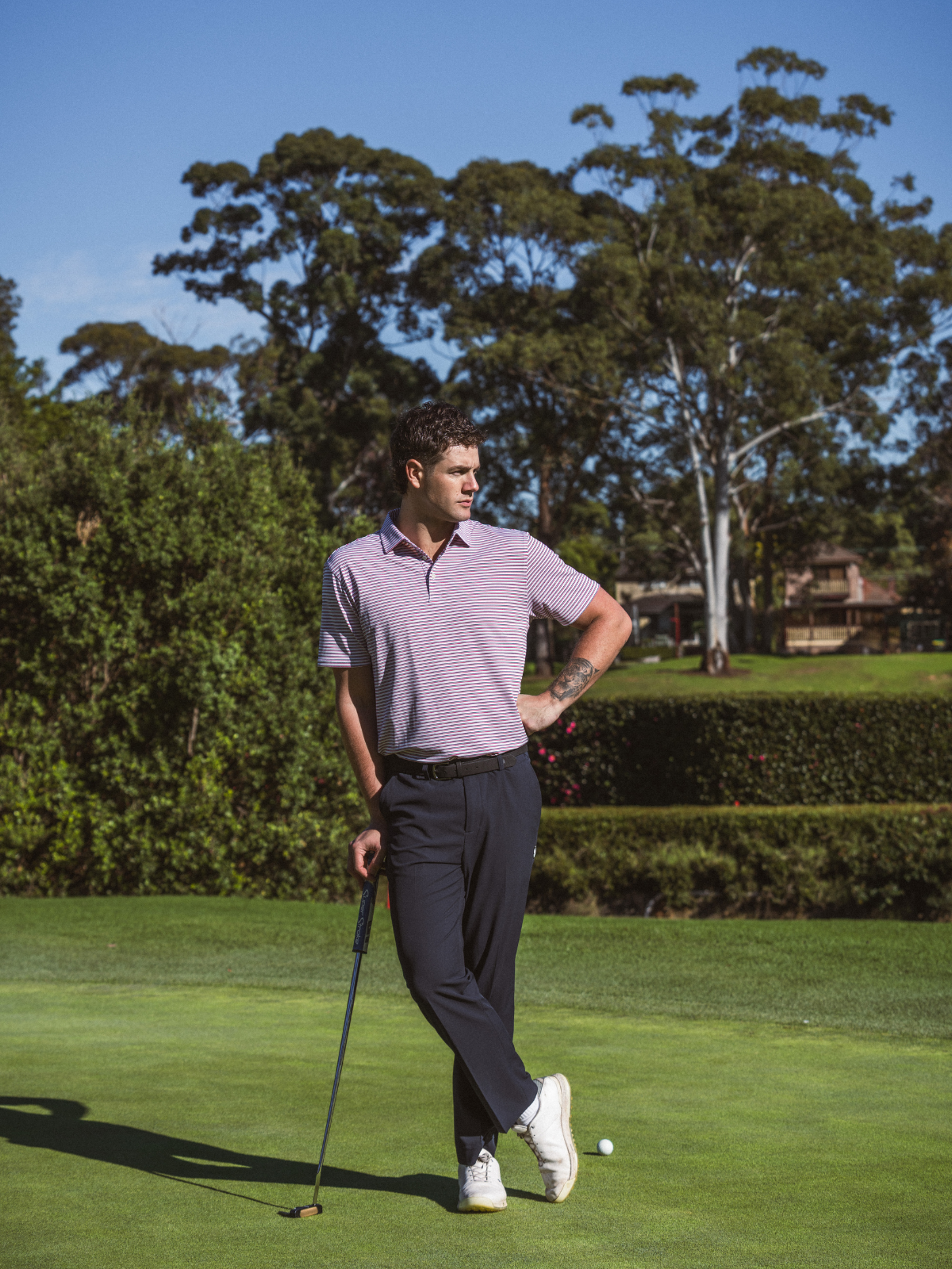 Man wearing Quiet Golf Teo Polo in red stripe, full length shot on golf course green