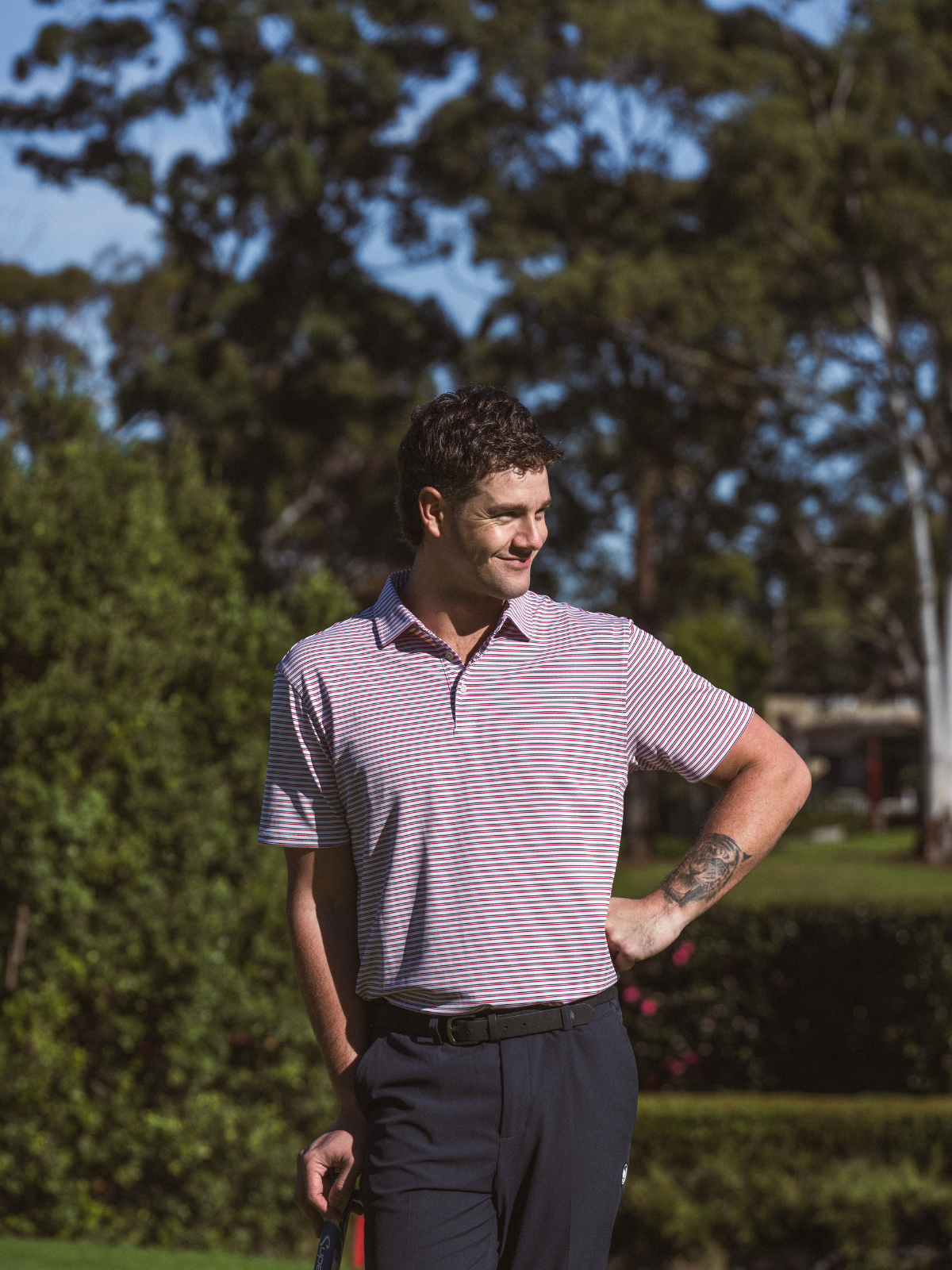 Man wearing Quiet Golf Teo Polo in red stripe, three quarter shot on golf course