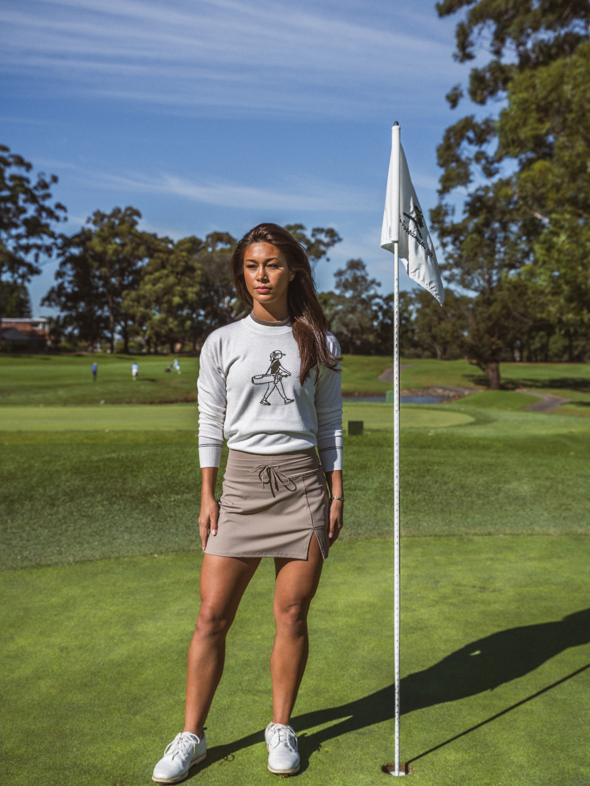 Woman wearing Draw & Fade Walking Girl Crewneck in white, full length shot on golf course green