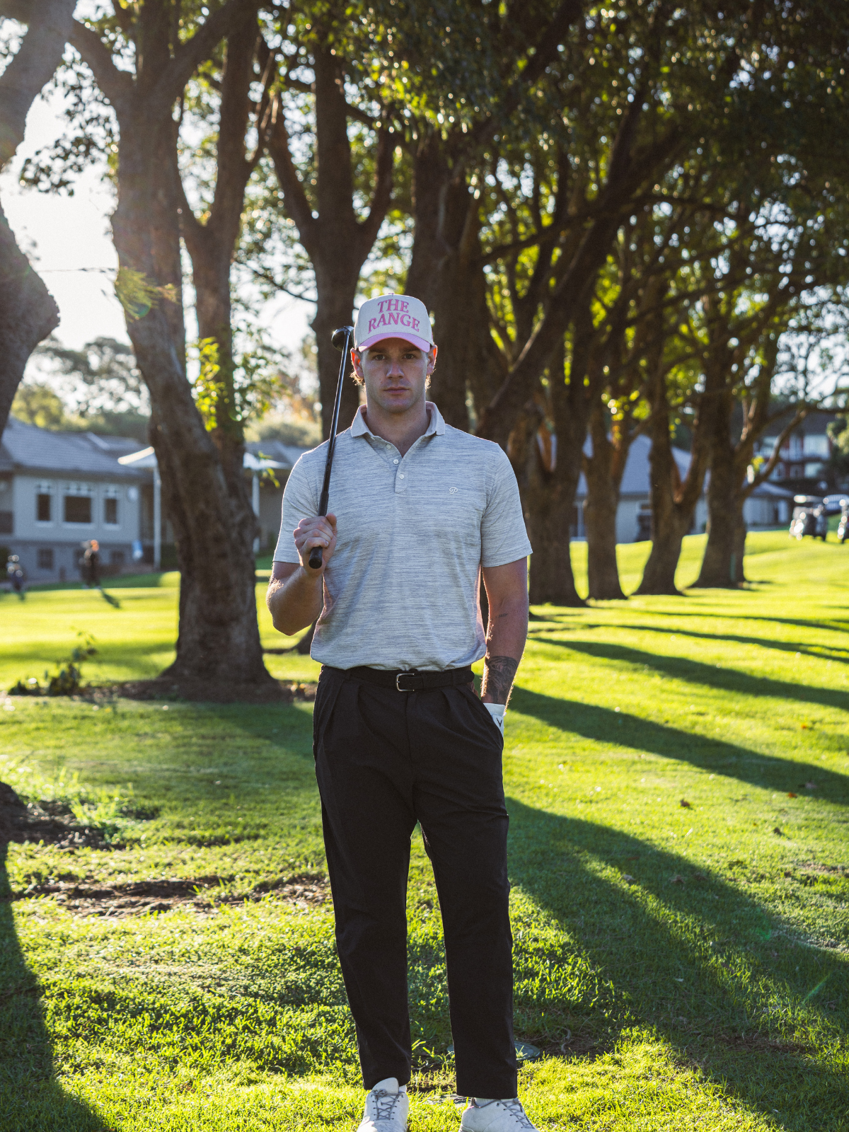 Man wearing Inland Grove The Range Hat in pink and white, full length shot on golf course fairway