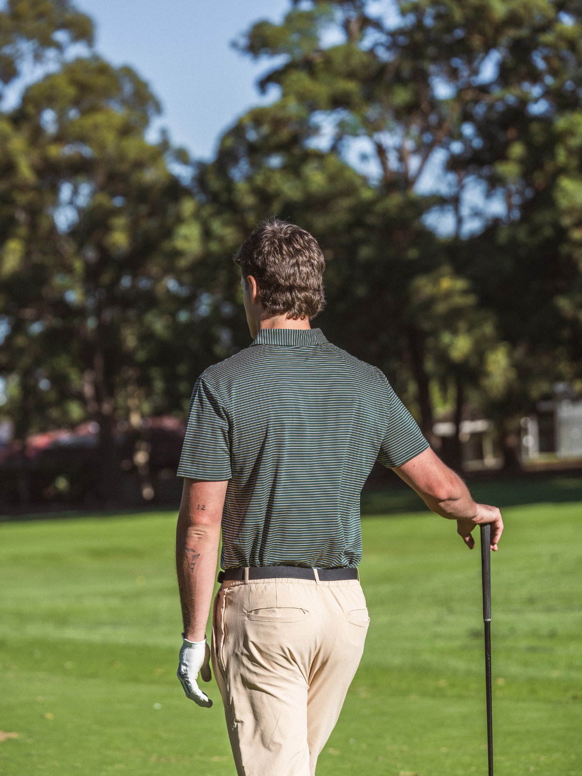Man wearing Quiet Golf Pine Polo on golf course, back view