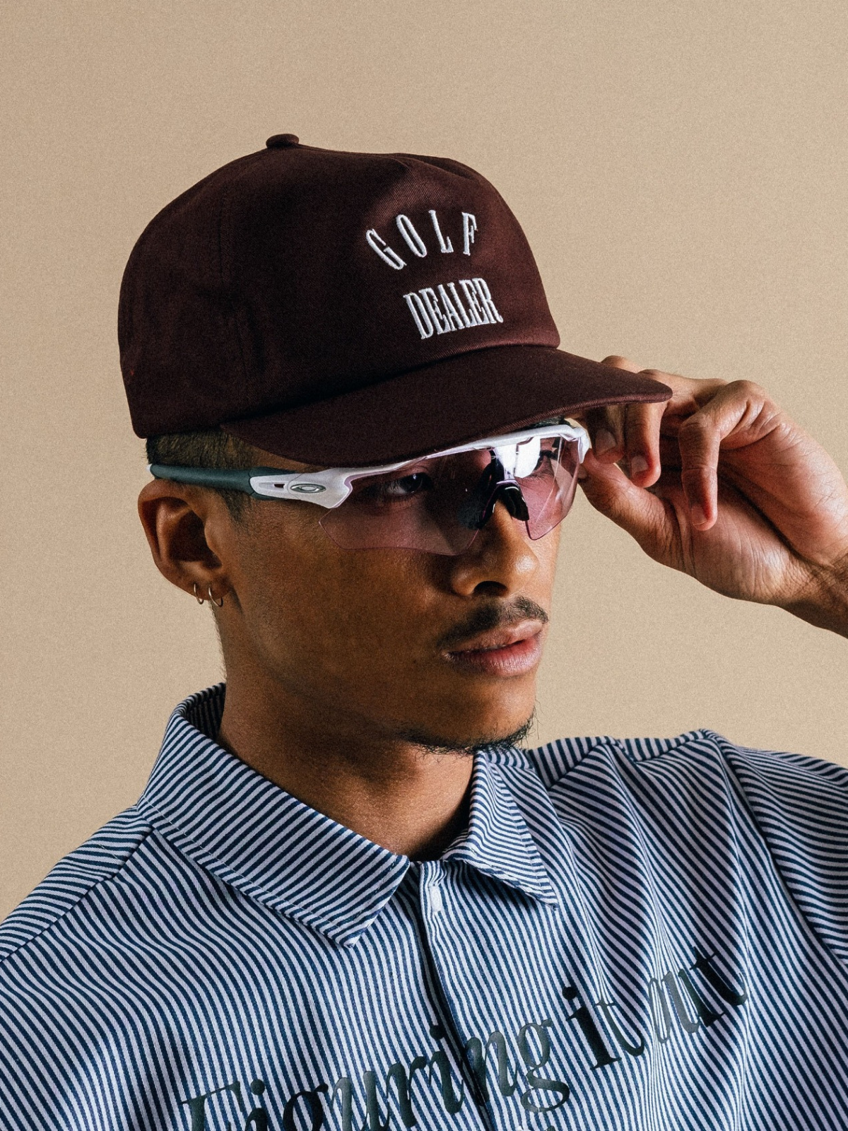 Model wearing brown Golf Dealer cap with blue polo, Students Golf, lifestyle view